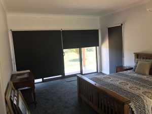 black indoor roller blinds in a bedroom
